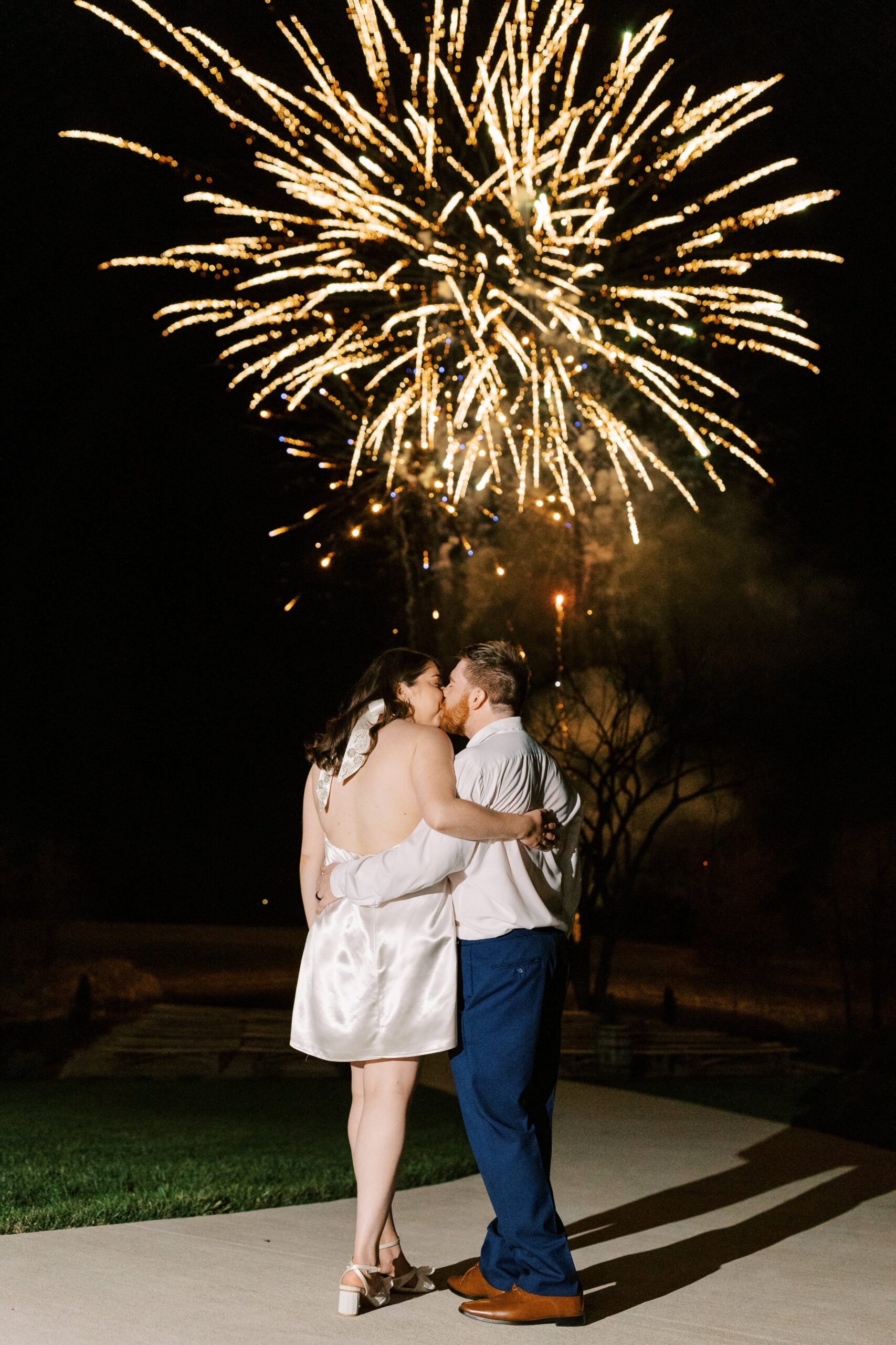 A newly married couple standing in front of fireworks on their wedding day at Cooper's Ridge Event Venue in Boonville, Missouri captured by Kiley Ann Photography.