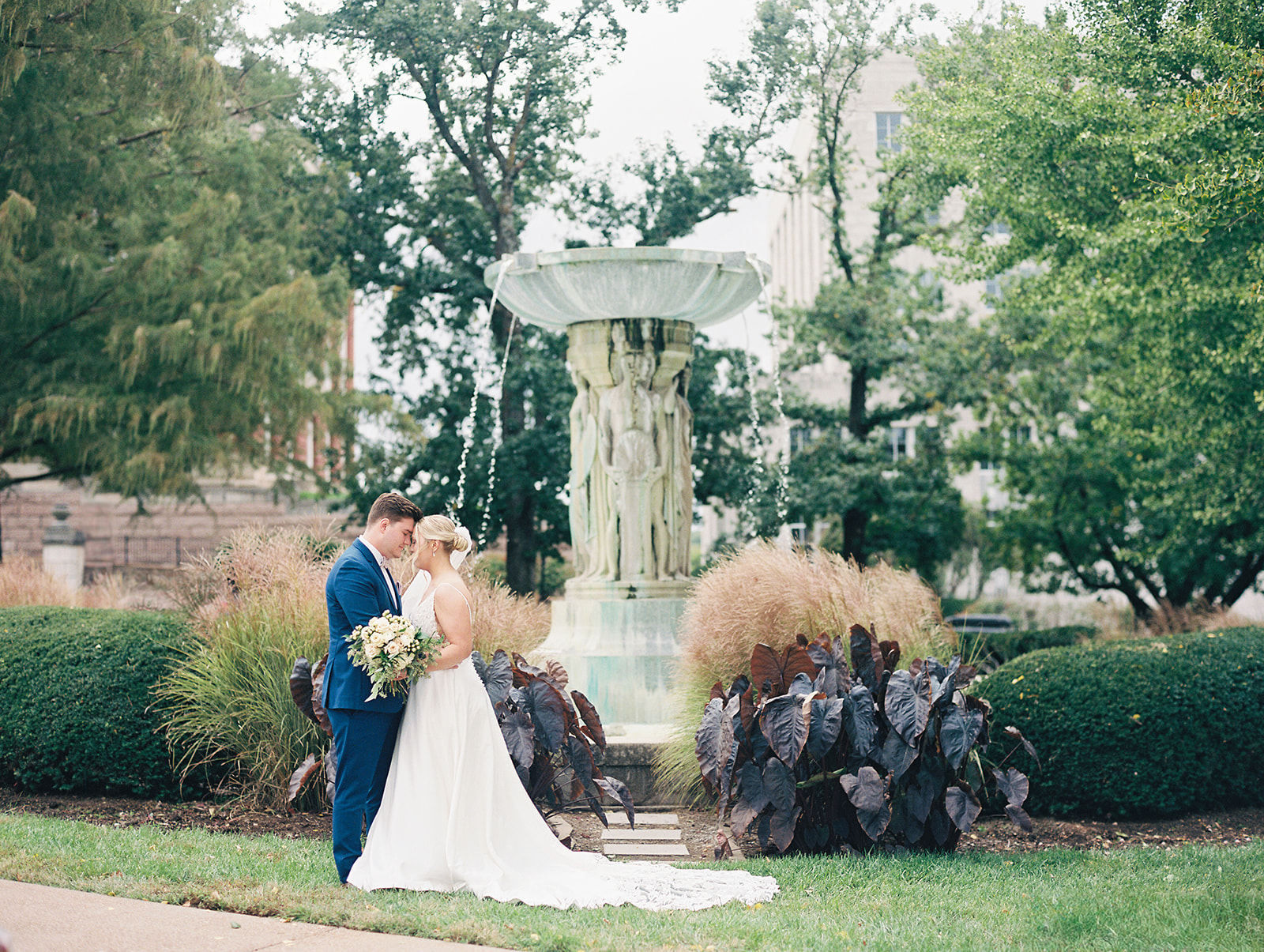 A husband and wife on their wedding day, standing at the Missouri Capitol during their bride and groom portraits. The photographer, Kiley Ann Photography, caught this image on film in Jefferson City, Missouri.