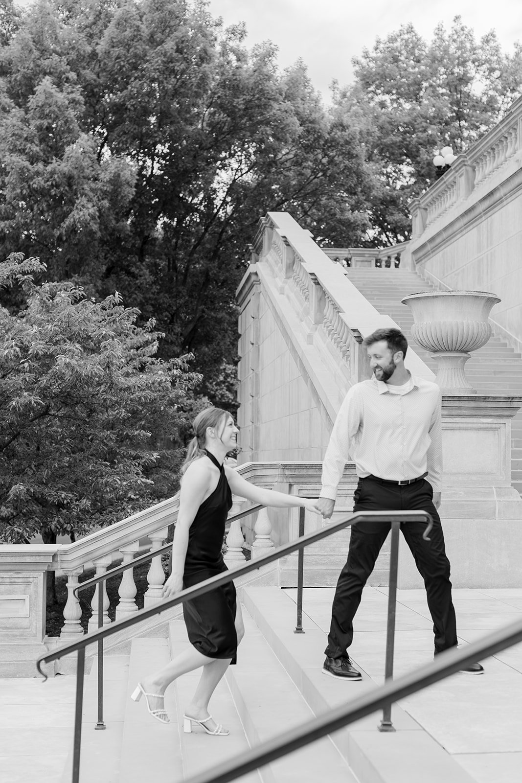 A couple joyfully walking up the stairs at the Missouri Capitol during their engagement session which allowed for versatility for engagement session posing