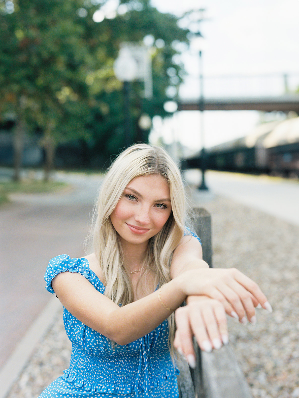 A high school senior wearing a blue dress posing for her portrait captured by Kiley Ann Photography in Jefferson City, Missouri at the Governor's Garden.