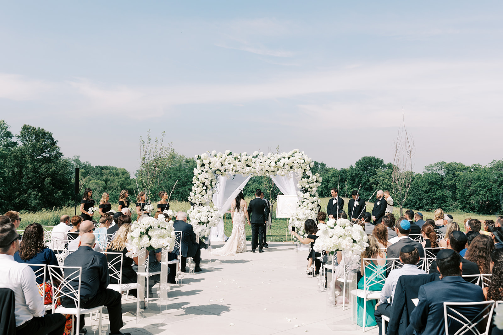 An outdoor wedding ceremony at the wedding venue White Iron Ridge in Kansas City, Missouri. The Photographer, Kiley Ann Photography, captured the Jewish ceremony traditions to emulate film.