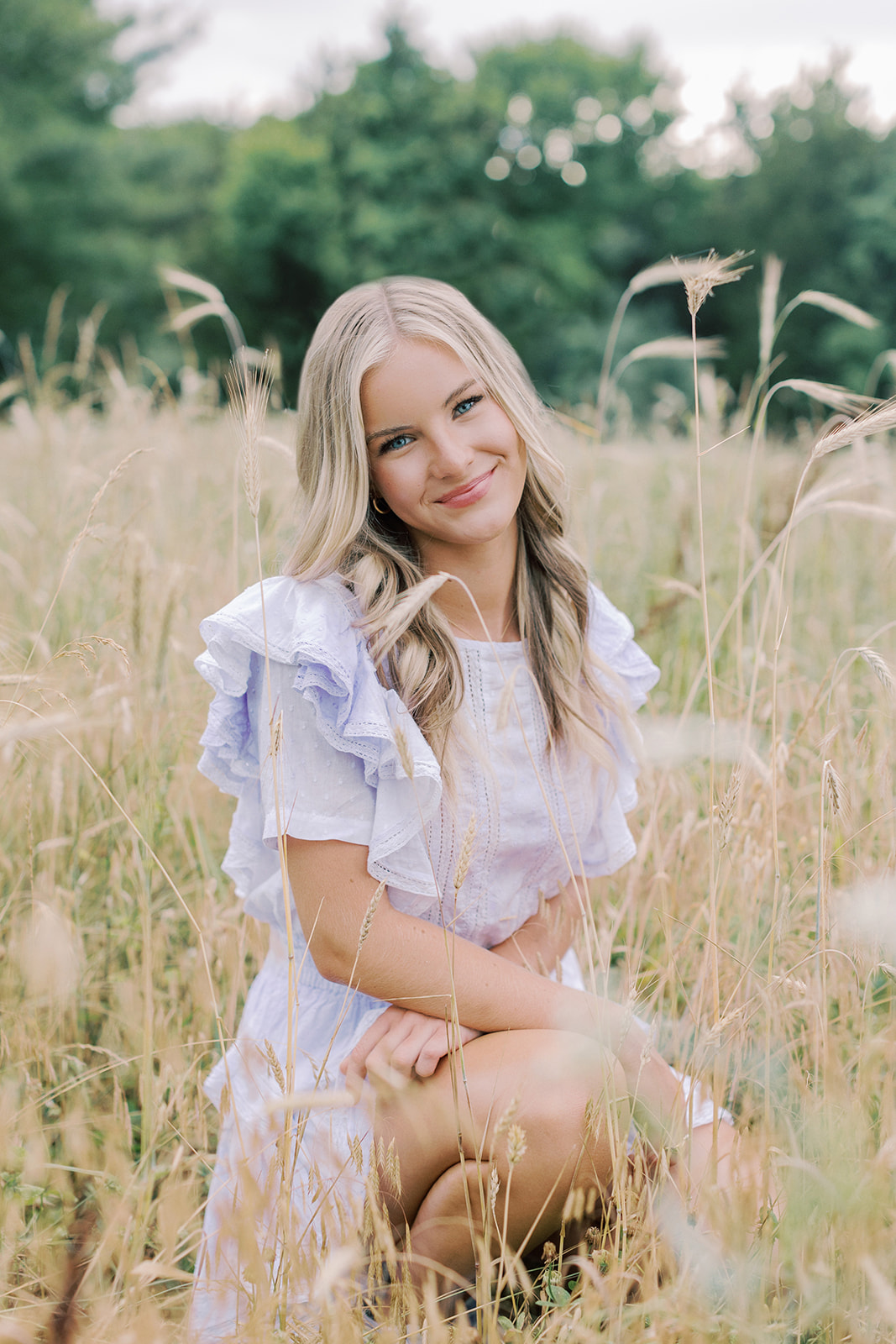 A high school senior posing in a field for her senior session captured by Kiley Ann Photography. This blog breaks down the average cost of a high school senior session and the different pricing variations for sessions.